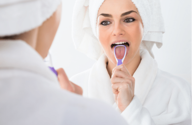 A Woman Looking In Mirror Cleaning Her Tongue