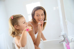 Mother and daughter in bathroom brushing her teeth