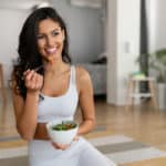 Young woman eating a healthy salad after workout.