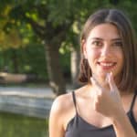 smiling Turkish woman is holding an invisalign bracer