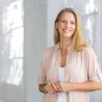 Portrait of happy beautiful lady in a pink shirt with toothy smile standing