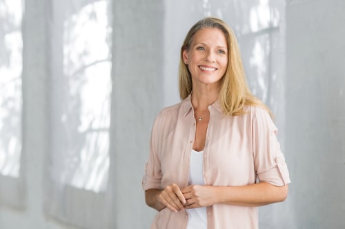 Portrait of happy beautiful lady in a pink shirt with toothy smile standing