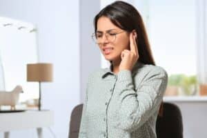 A woman with TMJ and ear problems touching her ear