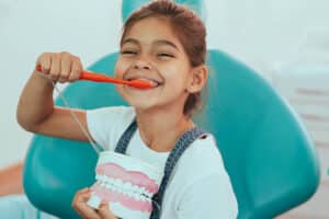 A young girl smiling and holding a toothbrush after getting dental sealants