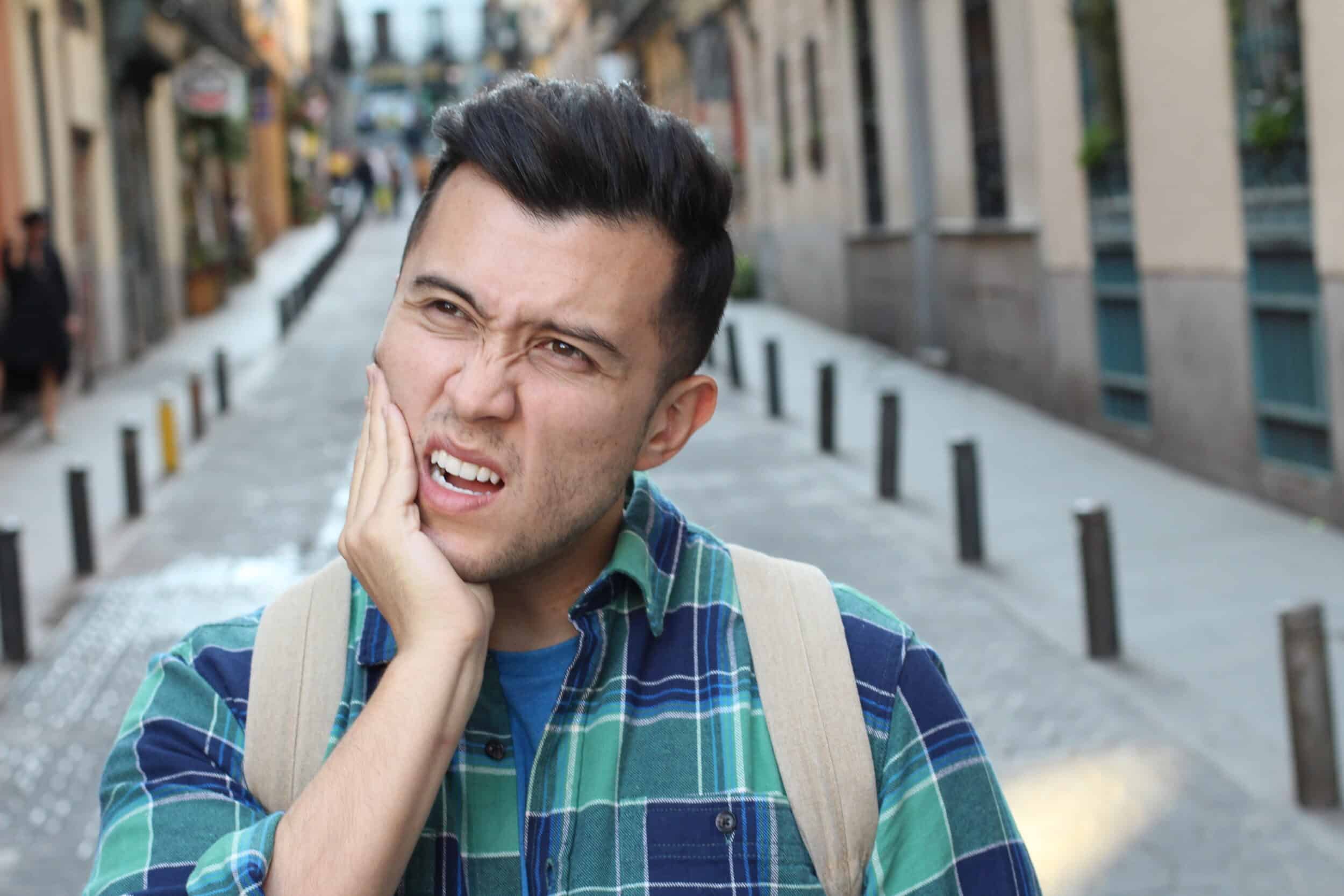 A man with a TMJ disorder holding his jaw